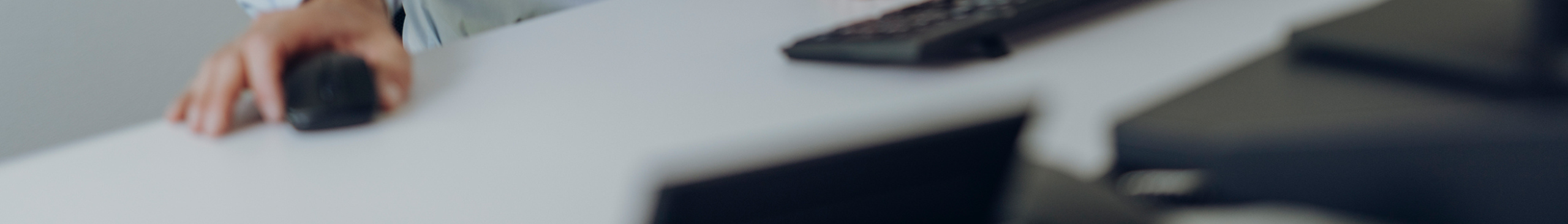 Ausschnitt eines Bürotisches mit zwei Händen, die Maus und Tastatur bedienen.
